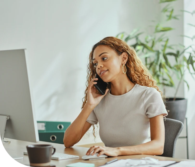 woman holding cell phone and sitting at a desk
